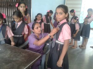 Female volunteer from SSVS measuring student's vitals during health camp